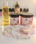 Bubble gum body scrub jars, vitamin E oil, pastel beads, and skincare products on white background